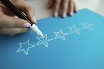Person draws five stars in the recommendations with white felt-tip pen reviews