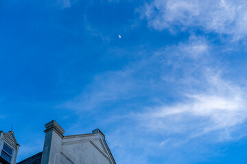 Half moon in the distant sky with top of historic building in the corner and mostly negative space