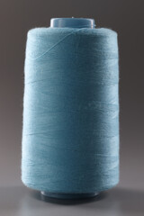 Texture of blue thread in sewing spool on gray background. closeup