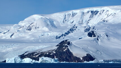 Icebergs at the base of a snow covered mountain, at Cierva Cove, Antarctica