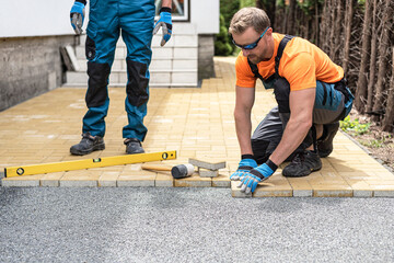The worker laying the interlocking paving stone.