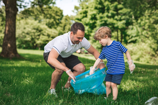 father and boy recycling outdoors together on a summer day at the parc - Powered by Adobe