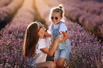Happy family in purple lavender field. young beautiful mother and child Girl enjoy walking blooming...