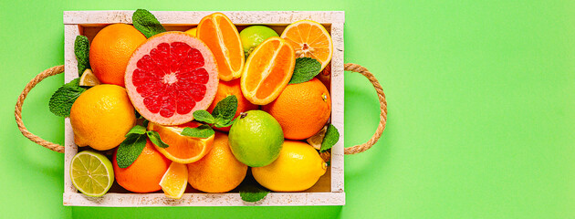 Fototapeta na wymiar Fresh citrus fruits with leaves: lemons, oranges, mandarins, grapefruit, lime in wooden box