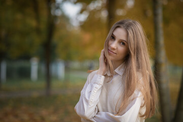 Portrait of a young beautiful girl in early autumn in the park.