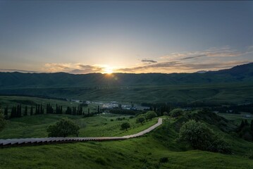 Beautiful scene of large green fields with long descending stairs against mountains and a sunset sky