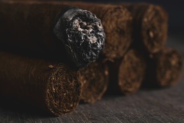 Shallow focus of a burning cigar on a brown wooden table
