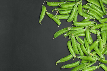 Fresh green peas with pod in bowl on black background