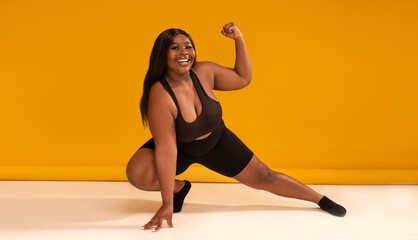 Happy plus size woman posing in sporty black fashionable clothes, smiling to the camera. Sports and...