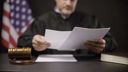 Male judge reading papers with testimony to make the right decision, announcing verdict