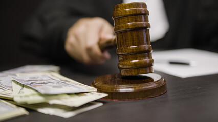 Corrupt judge striking wooden hammer, dollar bills lying on court desk, close-up