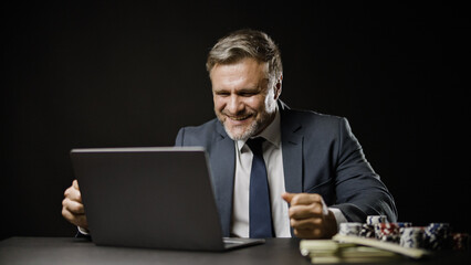 Businessman celebrating successful online bet, winning in poker game, gambling