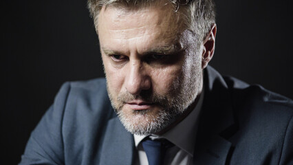 Depressed man in business suit sitting alone in dark room, victim of fraud