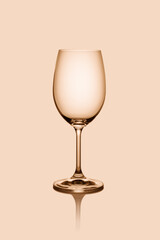 Empty wine glass isolated on the light background toned beige.