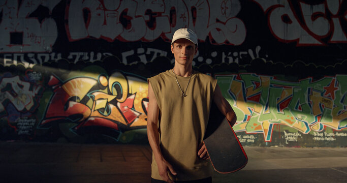 Attractive man skateboarding at skate park. Teenager looking on camera. 