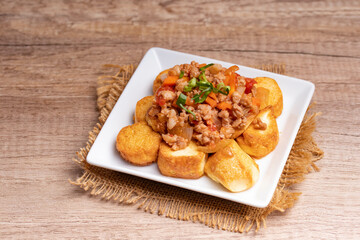 Fried tofu stir fried with ground pork and vegetables in white plate