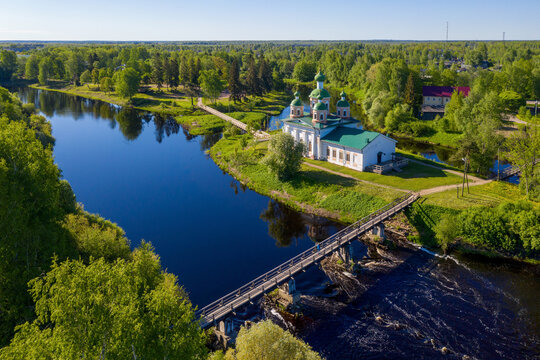 Aerial view of Smolensky cathedral and wooden bridge over Olonka river on sunny summer day. Olonets, Karelia, Russia.