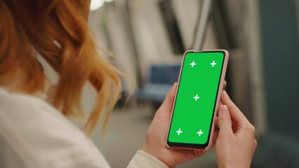 Over the sholder shot woman watching green screen phone on the underground. Woman using technology on the subway. Technology content. - Powered by Adobe