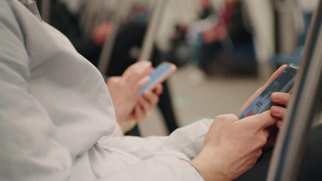 People using smartphone in subway. Lifestyle concept. Activities in public transport. Couple addicted to social network, technologies, media ignoring each other on a subway train.