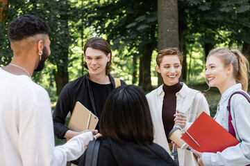 Multiethnic students with notebooks talking in park.