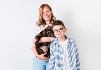 cute 8 years old boy studio portrait on white background with his Labrador Retriever dog and his mother