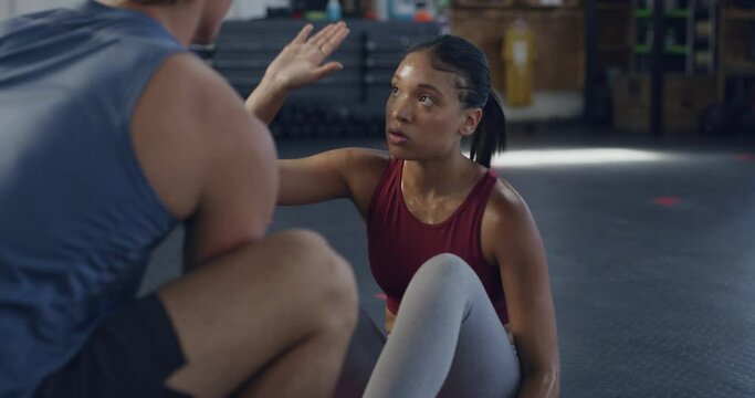 Motivated female exercising with her personal trainer or coach in gym. Inspired active fit woman training her core strength in a fitness center. Motivated athletic lady using a ball to workout