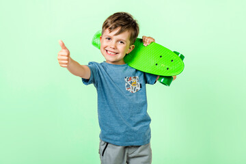 Little child sitting on a skateboard isolated on grey background