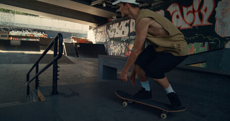 Fototapeta premium Skate boarder doing tricks in bowl at urban skatepark. Rider training skills. 