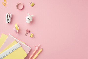 Back to school concept. Top view photo of school accessories copybooks pens ruler stapler binder clips adhesive tape and bunny shaped sharpener on isolated pink background