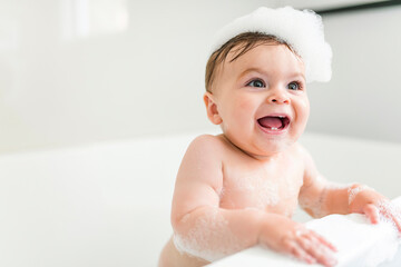 Baby boy bathes in a bath with foam and soap bubbles