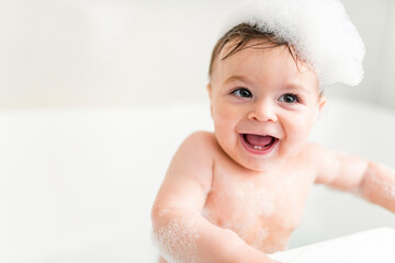 Baby boy bathes in a bath with foam and soap bubbles