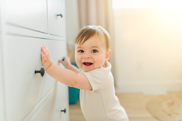 Adorable baby boy in white sunny bedroom in the morning at home