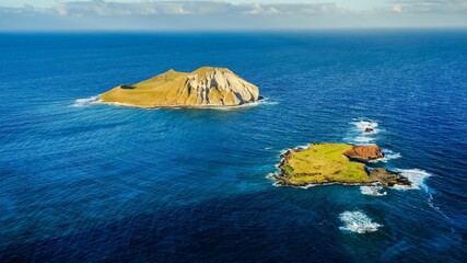 Aerial shot of two small islands surrounded by a deep blue ocean in the daytime