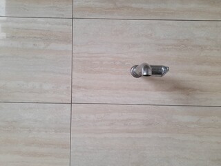 front view of the water faucet against the background of the ceramic wall in the bathroom of the...
