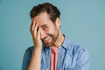 Young bristle man wearing shirt smiling and covering his face