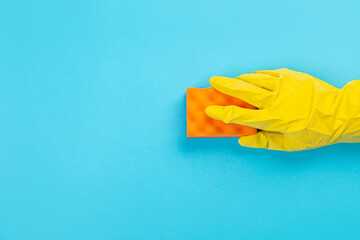 female hand in yellow rubber protective glove with micro fiber yellow rag for. washing dishes. A maid or housewife takes care of the house. general or regular cleaning. 