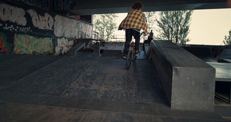 Active bmx rider performing tricks during freestyle session at skate park. 