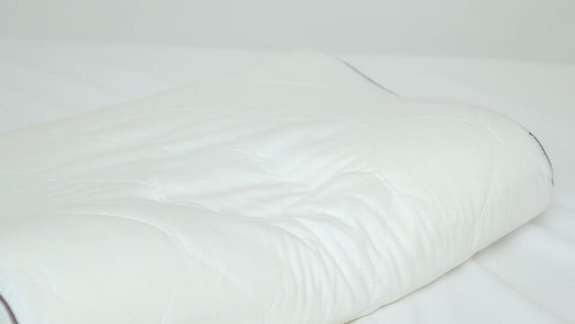 A woman presses her hand on an orthopedic pillow, the pillow evens out and takes its former shape