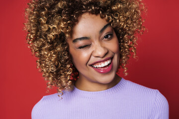 Young black woman with afro curls smiling and posing at camera