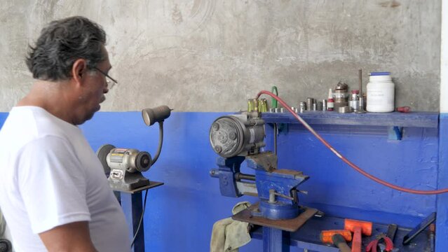 Mexican Senior Technician Specializing in Automotive Air Conditioning Compressors Repairing Customer's Truck AC Component in Workshop  | Slow Motion Footage mechanic testing newly repaired Compressor