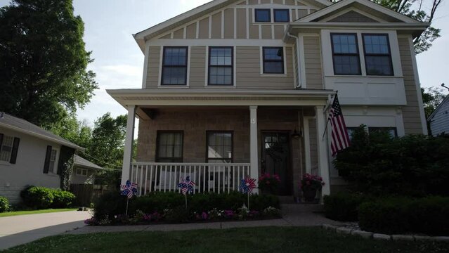 Pull away from a nice middle class house with American flag and patriotic decorations on a sunny summer day.