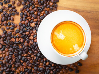 Top view of coffee cup has golden foam and mixed or blend coffee beans  on wooden backgrou