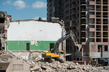 demolition old building by excavator near new construction of modern skyscraper