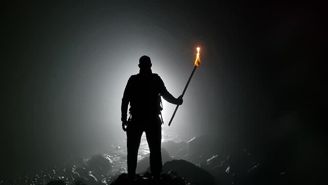 Young man with torch in cave facing the sea. It is called Cueva del Guincho, located in the city of Arucas. Island of Gran Canaria. Spain.