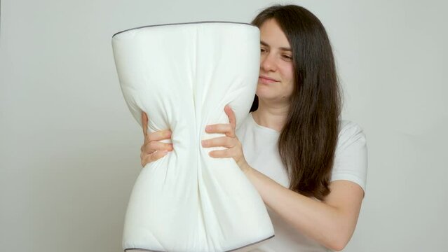 A woman compresses an orthopedic pillow, the pillow takes its former shape