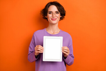 Photo of shiny sweet lady wear violet sweatshirt spectacles showing modern device empty space isolated orange color background