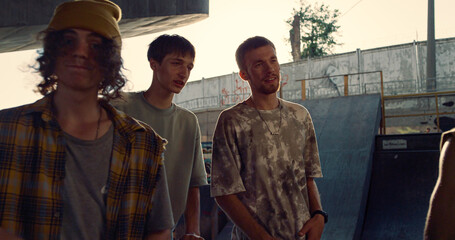 Calm hipsters walking together in skatepark. Boys enjoying time at fresh air