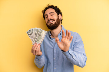 young man smiling happily, waving hand, welcoming and greeting you. dollar banknotes concept