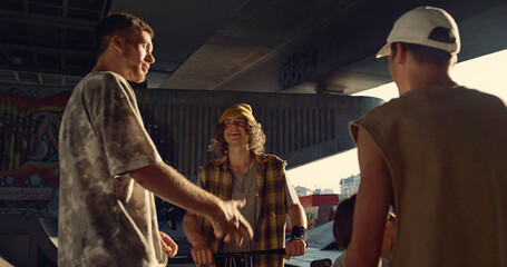 Youngster friends socializing together at skate park. Teens resting at skatepark