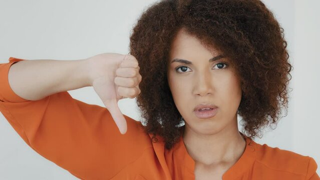 Portrait African American disgust dissatisfied upset angry frustrated disappointed woman with curly hair showing thumb down bad negative refuse irritation reaction girl looking camera dislike gesture